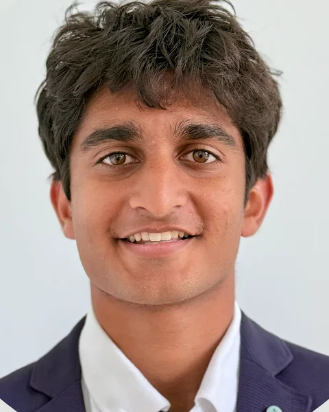 Aarav Sekhri, smiling, wearing a navy blazer over a white collared shirt.